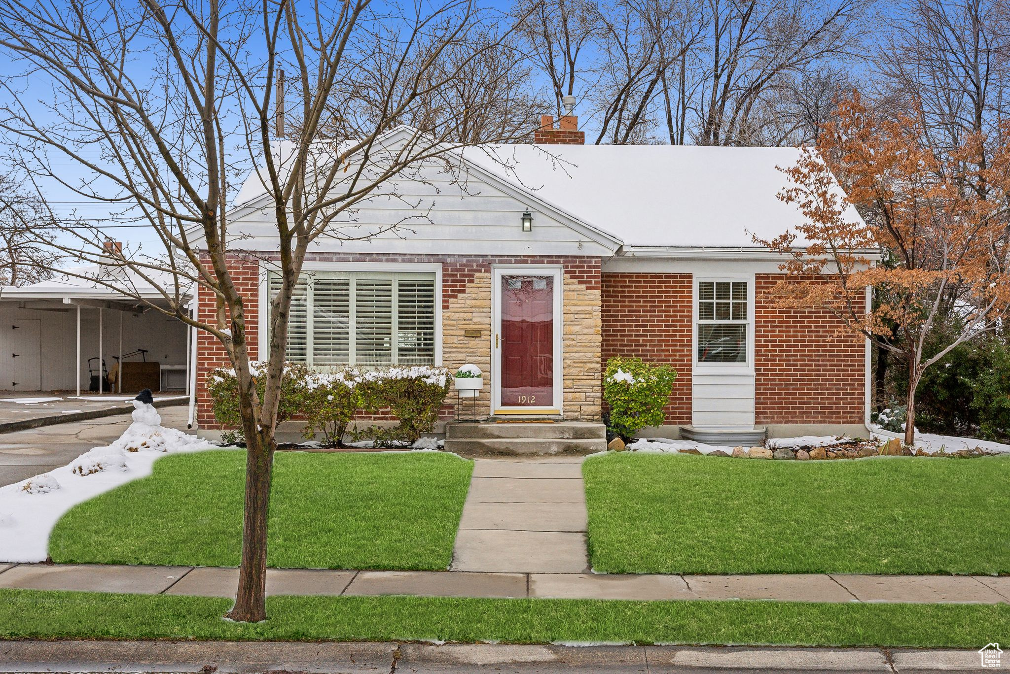 View of front of house featuring brick siding, a chimney, and a front yard