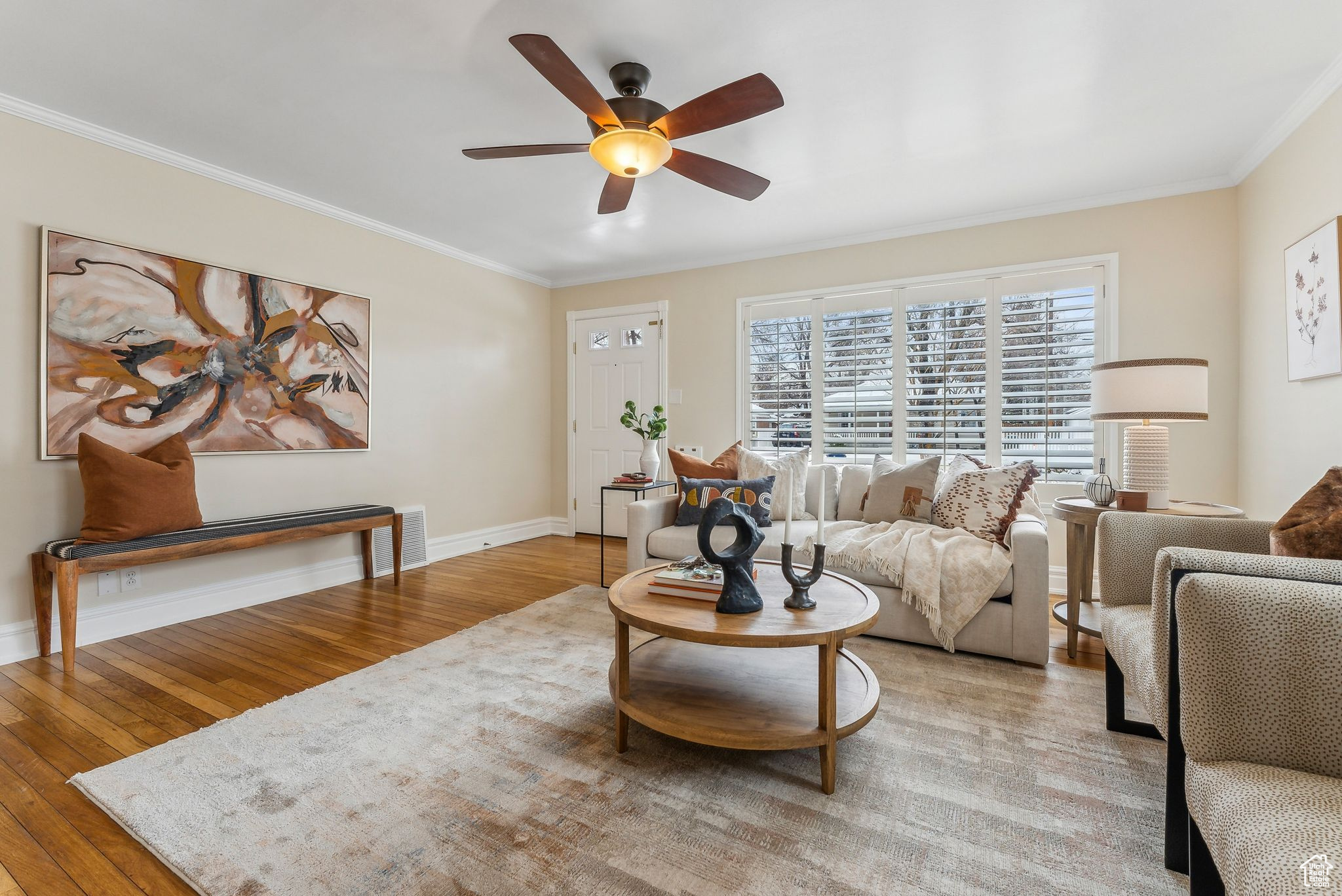 Living area featuring visible vents, ornamental molding, a ceiling fan, wood finished floors, and baseboards