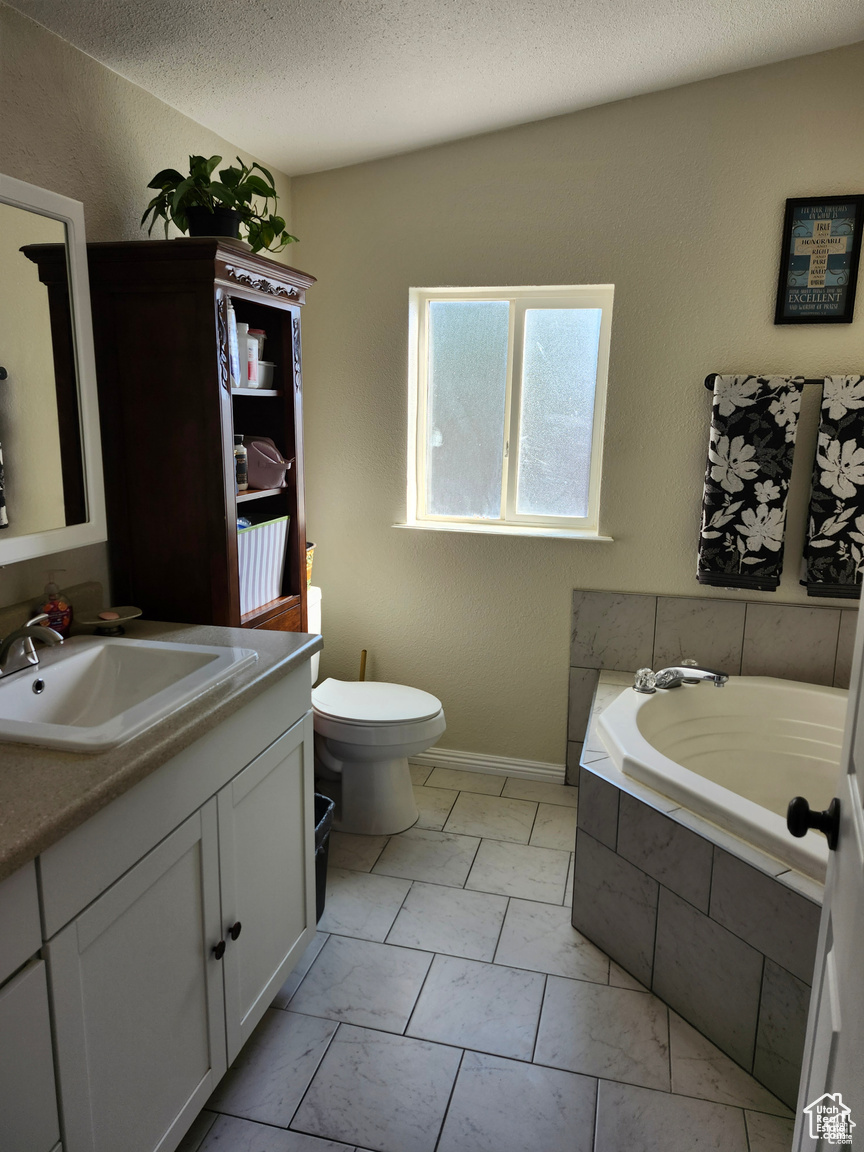 Full bathroom featuring a bath, toilet, a textured ceiling, and vanity