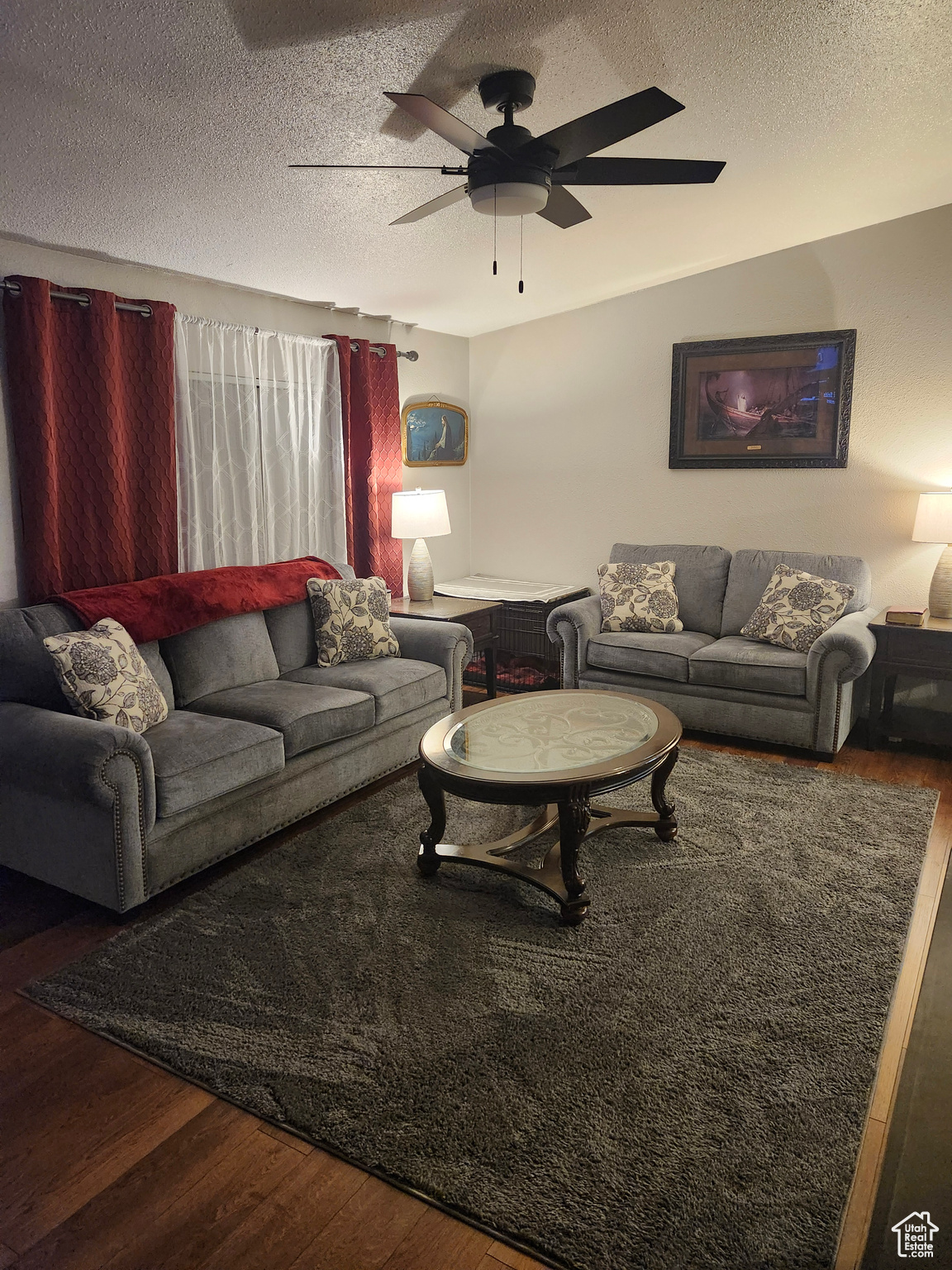 Living area with ceiling fan, wood finished floors, and a textured ceiling