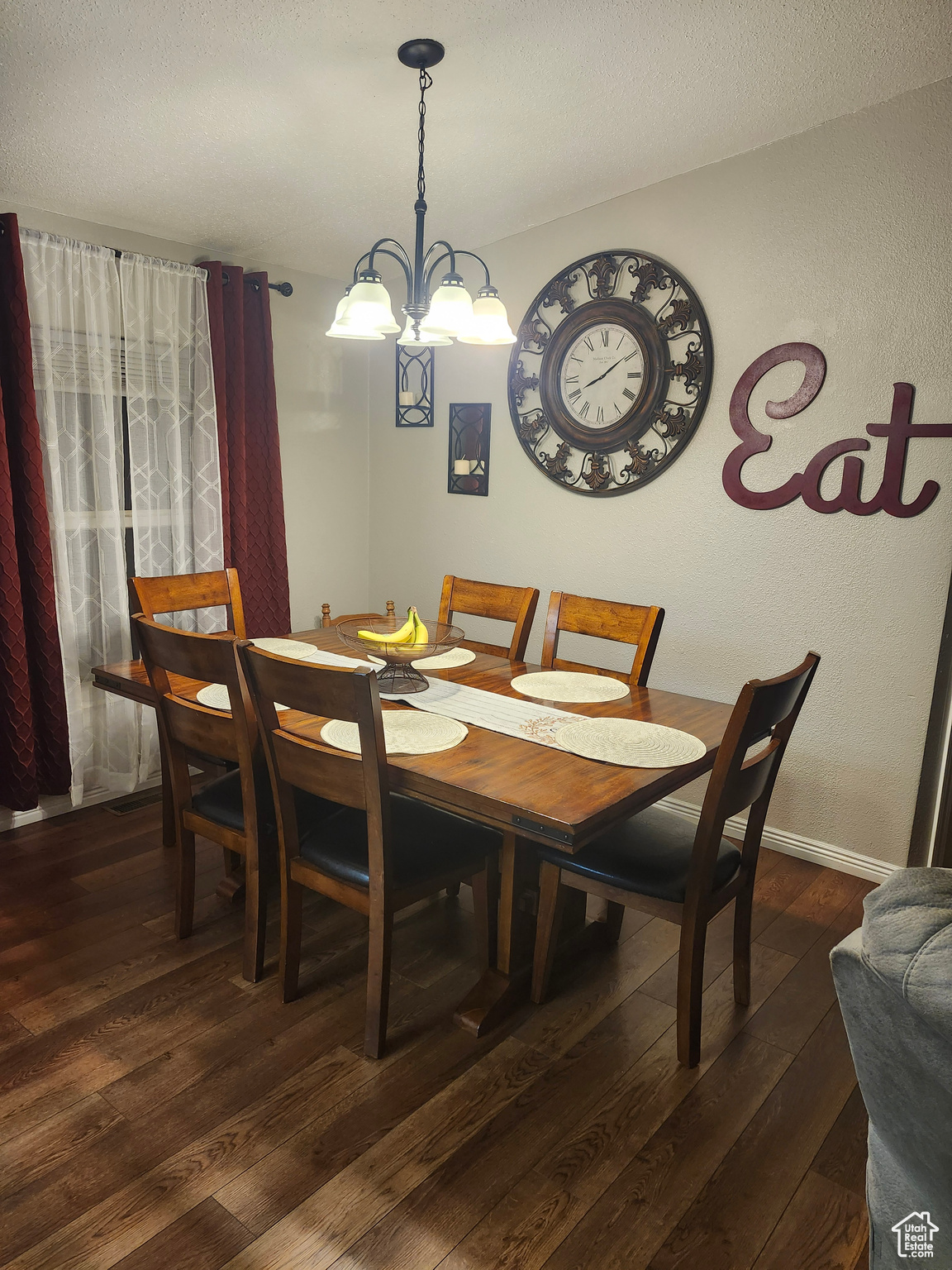 Dining room with dark wood finished floors, a chandelier, a textured ceiling, and baseboards