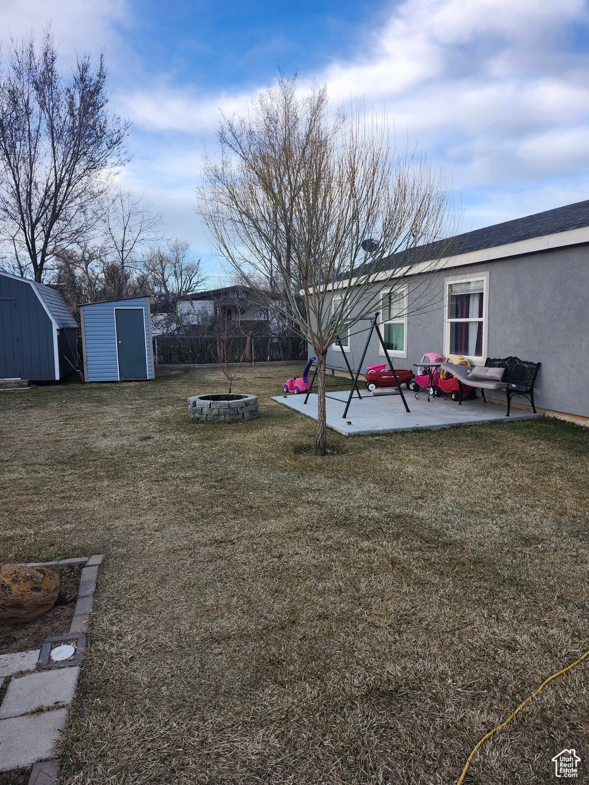 View of yard with an outbuilding, fence, a fire pit, a storage shed, and a patio area