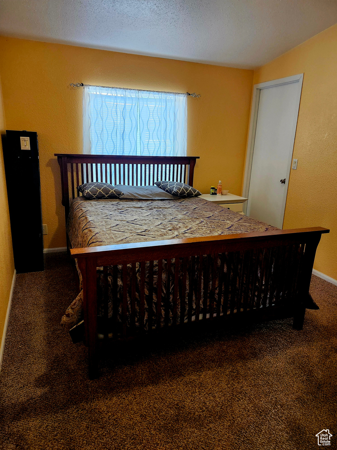 Bedroom with baseboards, carpet, and a textured ceiling