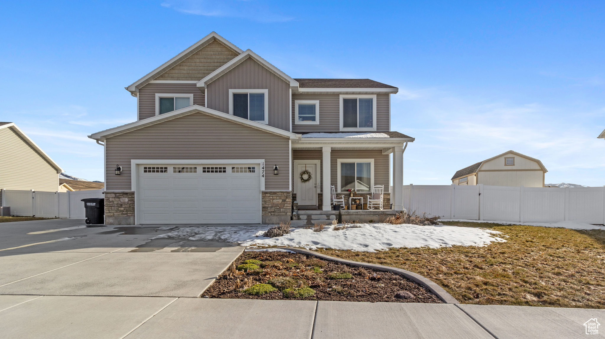 View of front of home with siding, covered porch, concrete driveway, and fence