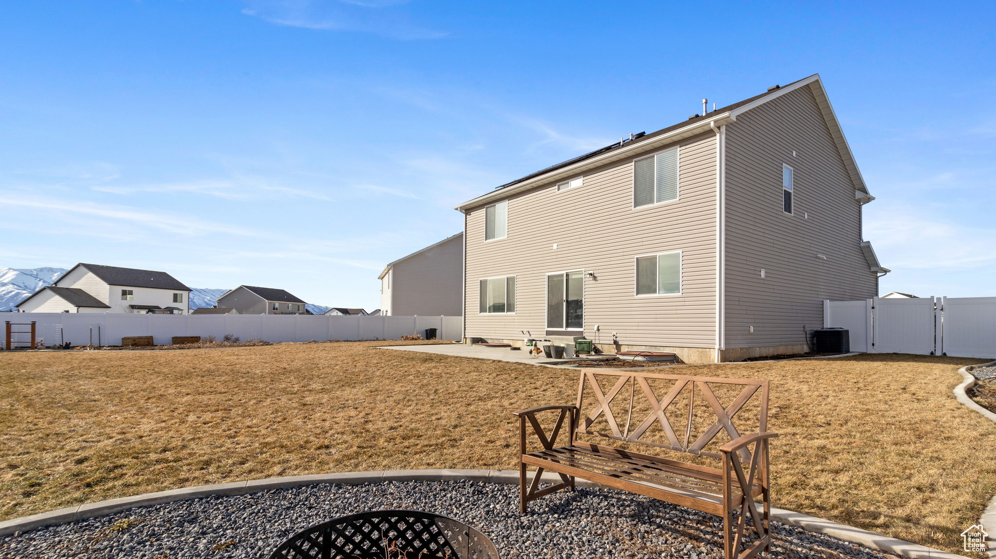 Rear view of house with a lawn, a gate, a patio, a fenced backyard, and central AC unit