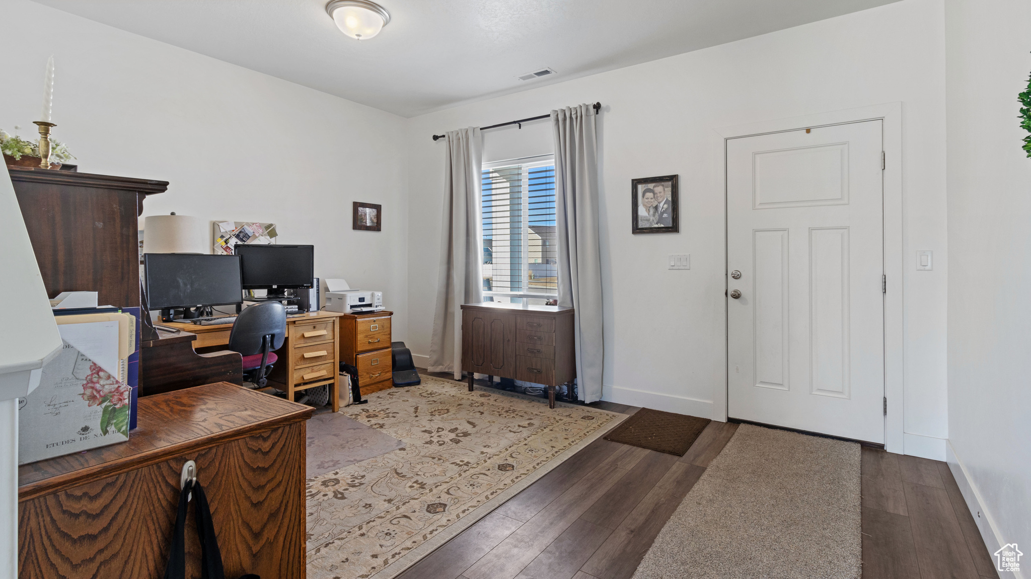 Office with wood finished floors, visible vents, and baseboards