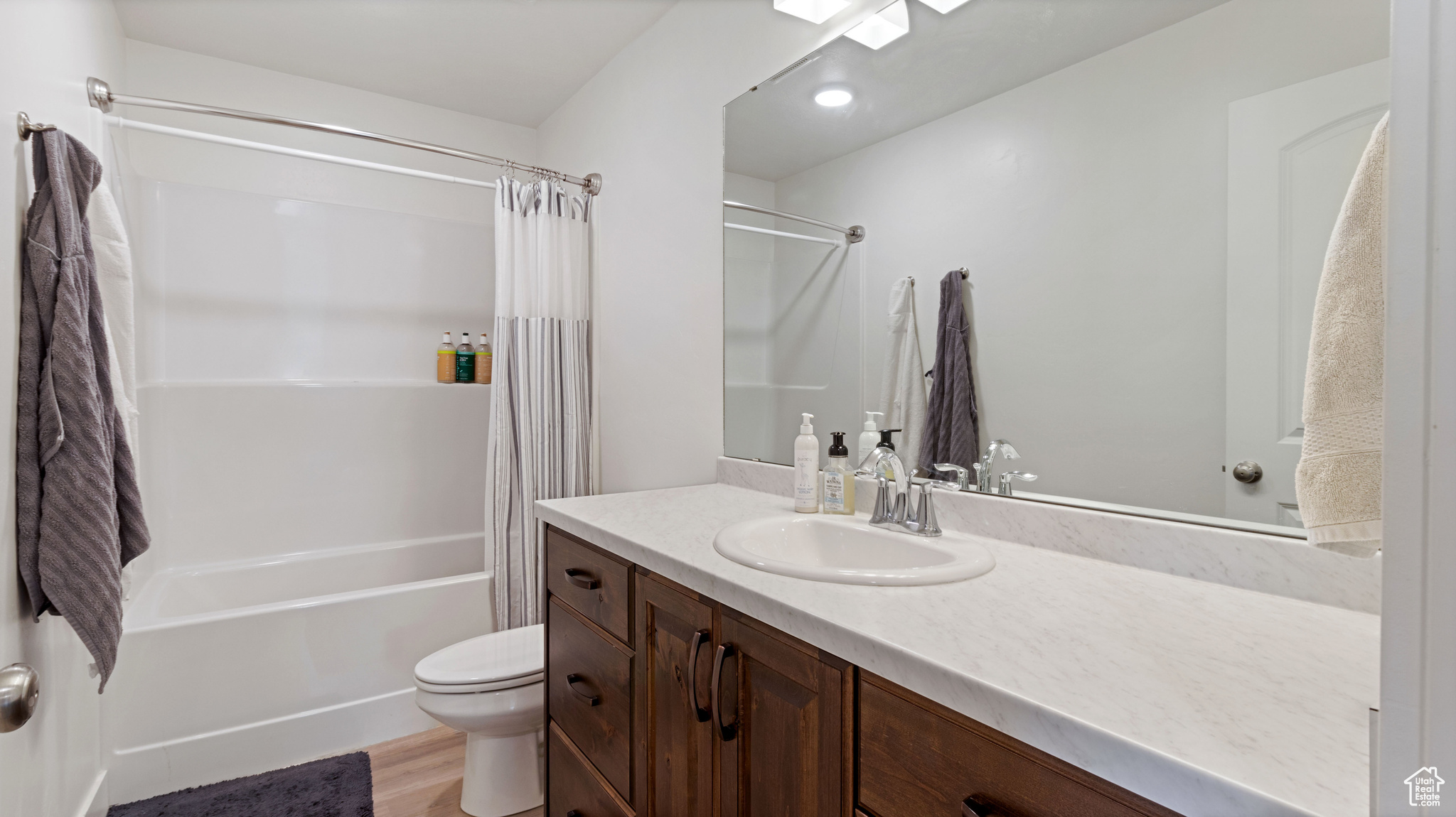 Full bathroom featuring vanity, toilet, shower / tub combo, and wood finished floors