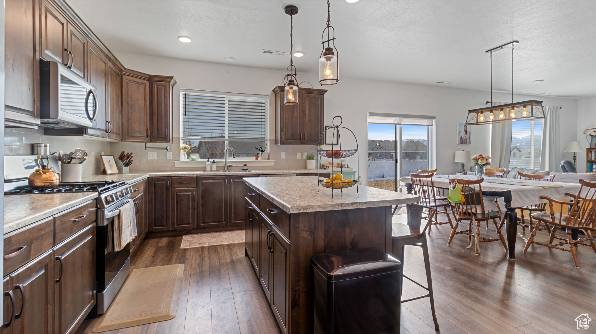 Kitchen with a sink, a kitchen island, dark wood-style floors, appliances with stainless steel finishes, and light countertops