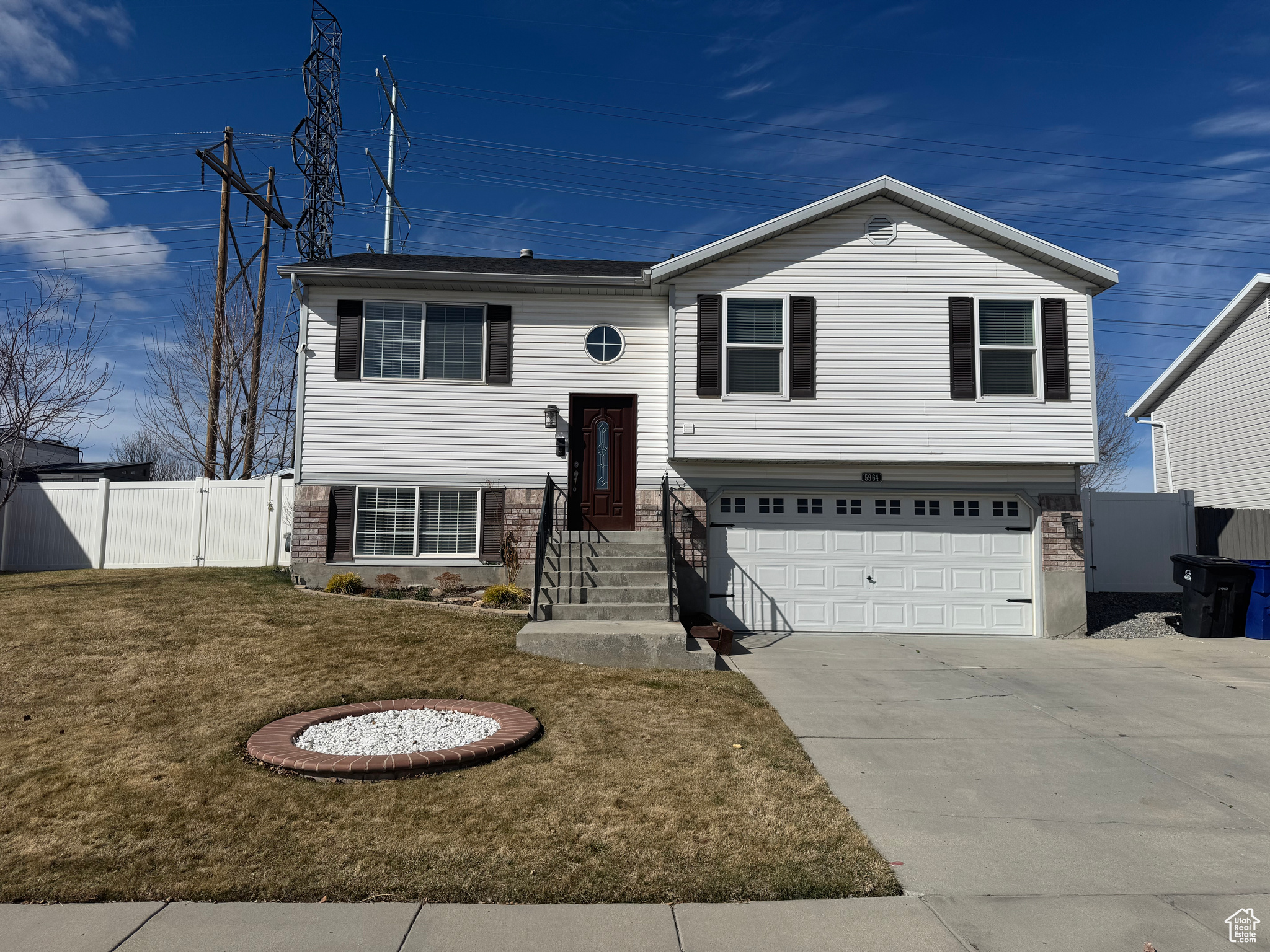 Raised ranch with an attached garage, concrete driveway, a front lawn, and fence