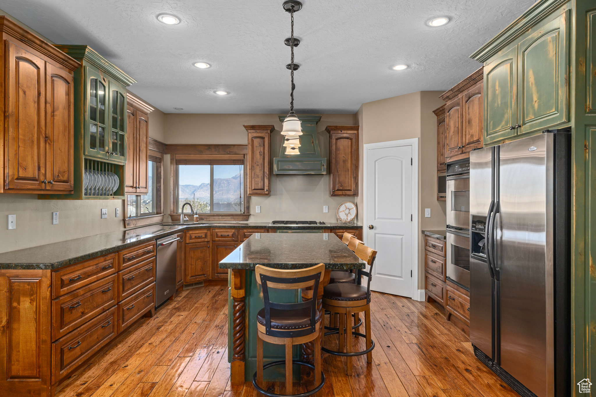 Kitchen with stainless steel appliances, a kitchen island, hardwood / wood-style floors, and custom range hood