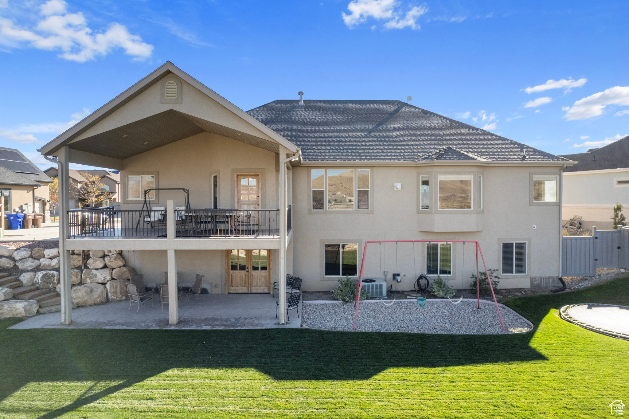 Rear view of house featuring stucco siding, a lawn, a patio, and a shingled roof