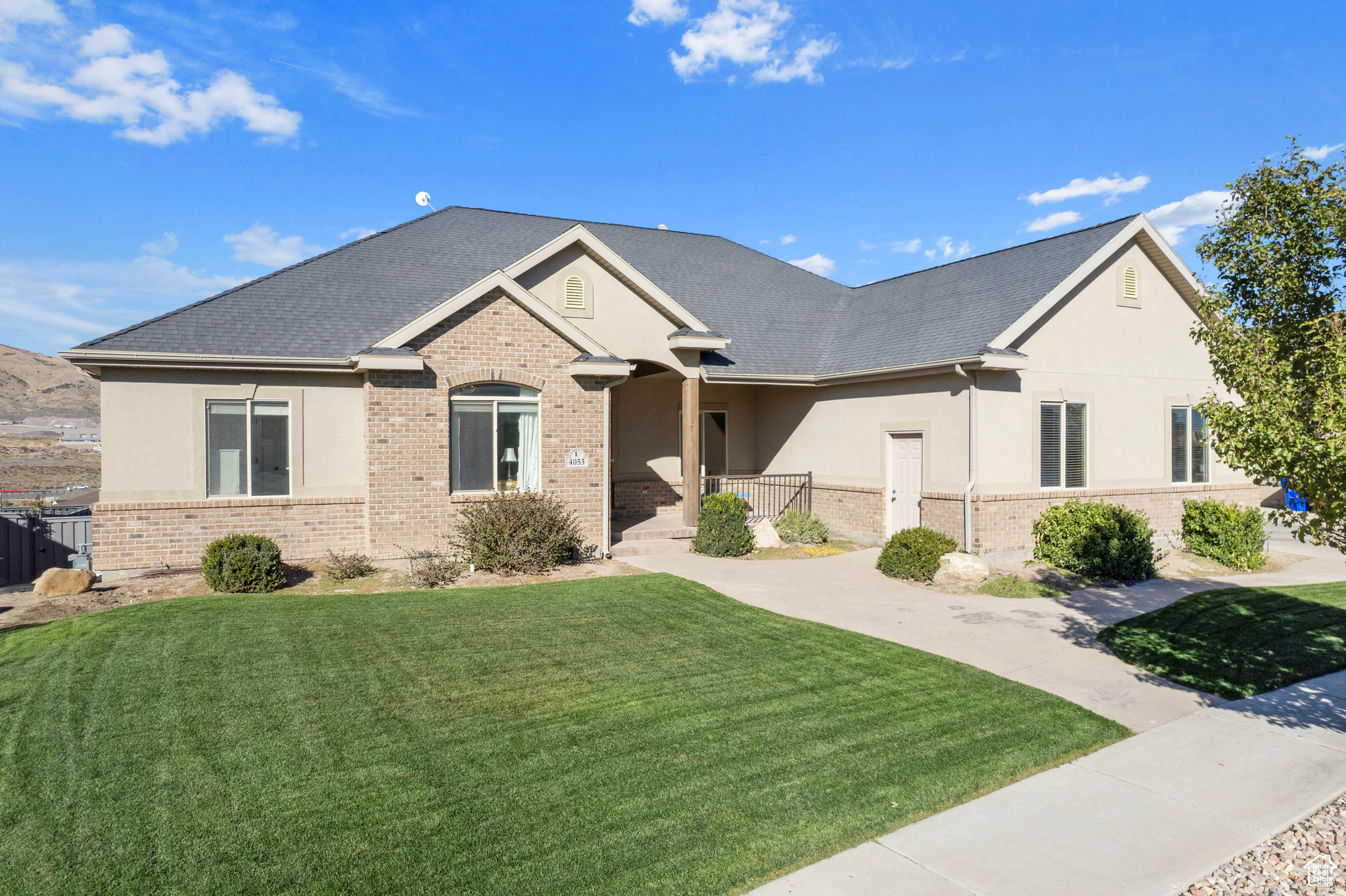 View of front of house featuring stucco siding, brick siding, and a front lawn