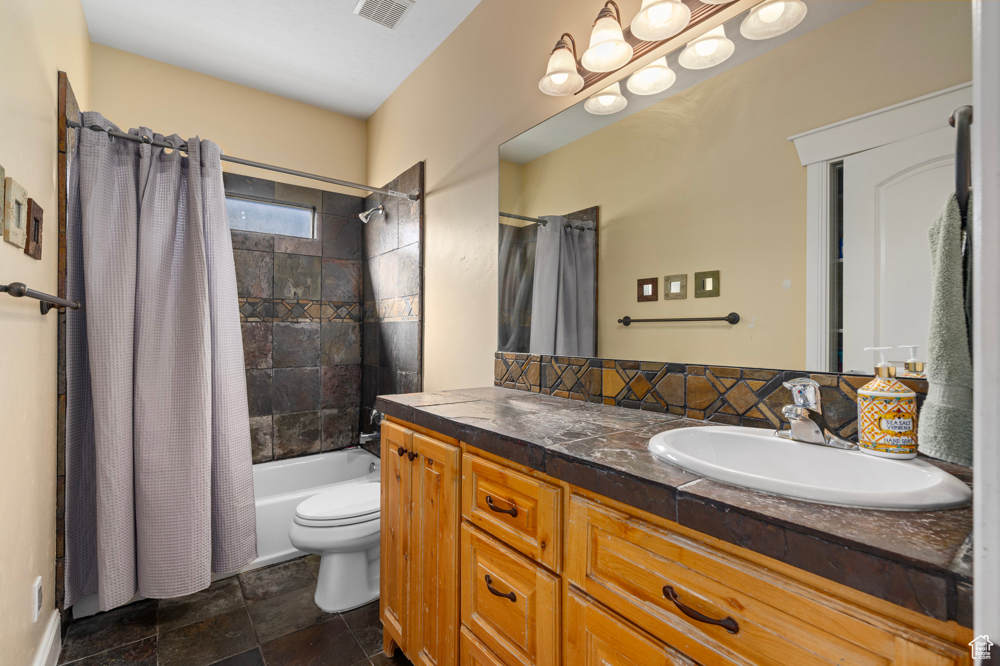 Bathroom with visible vents, shower / tub combo with curtain, toilet, a sink, and double vanity