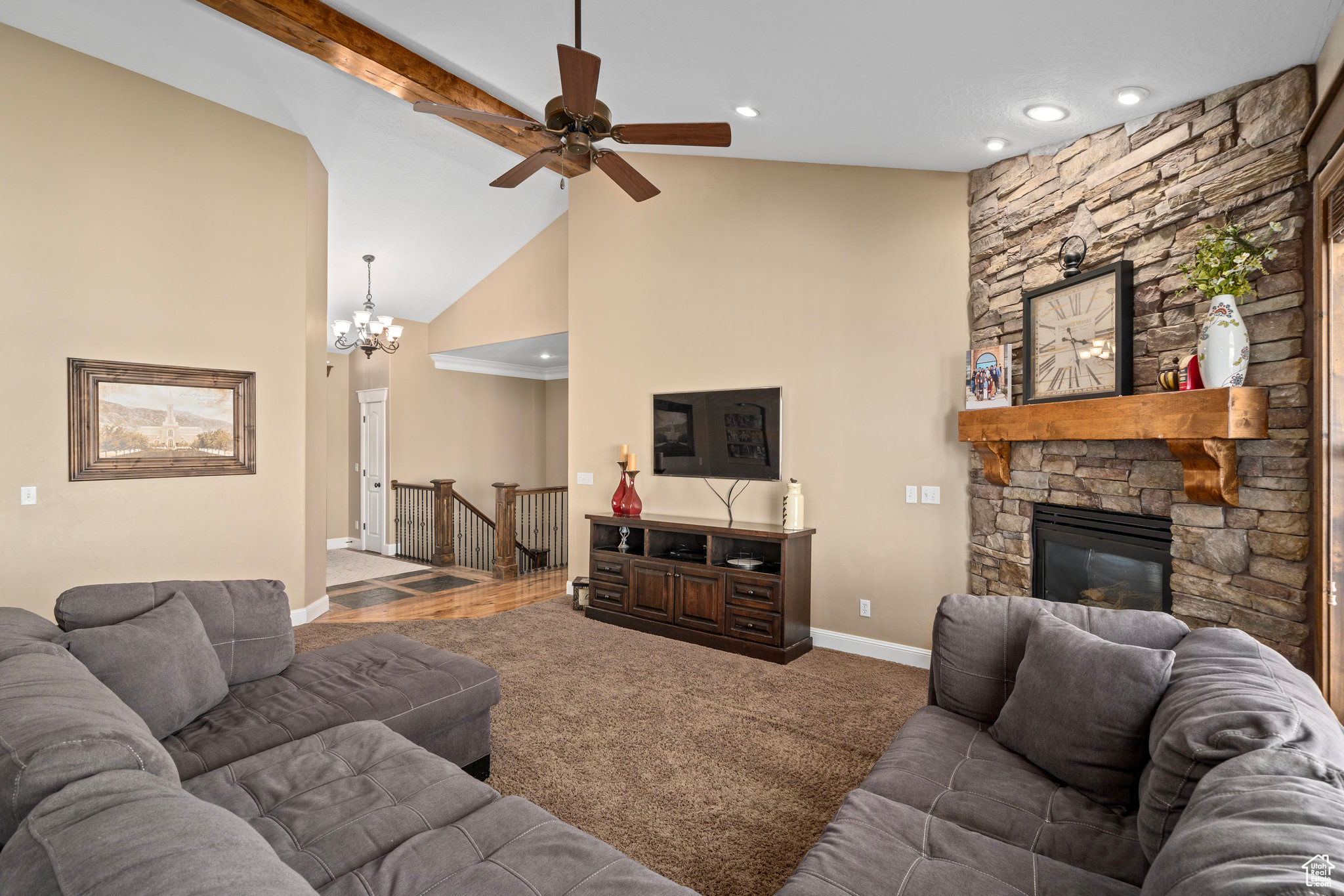 Living area with baseboards, carpet floors, high vaulted ceiling, a stone fireplace, and beamed ceiling
