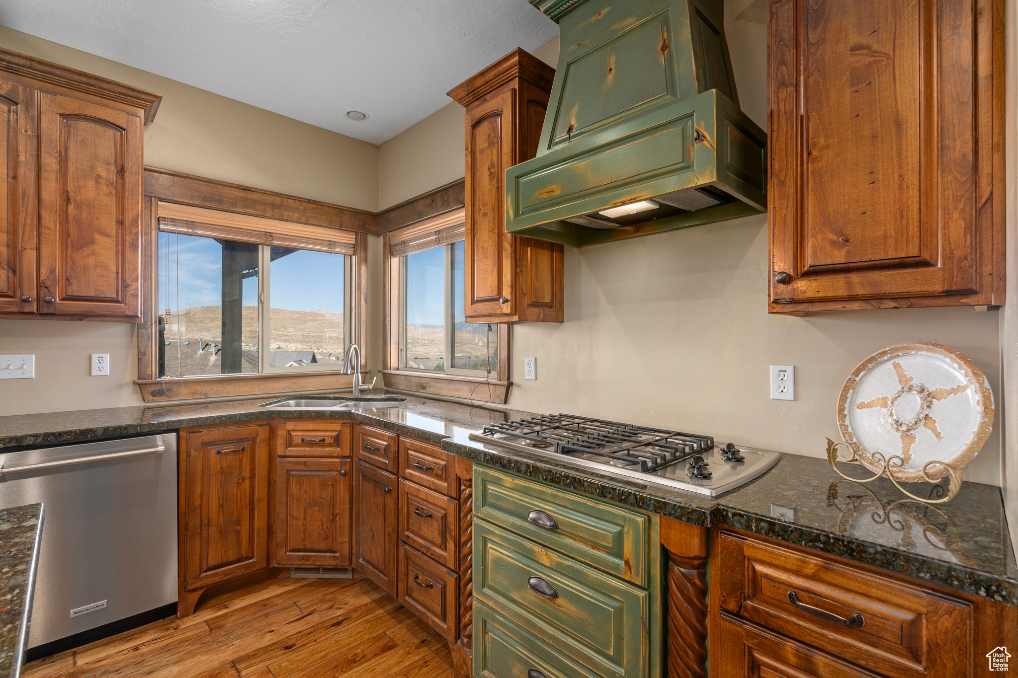 Kitchen featuring custom range hood, a sink, stainless steel appliances, light wood-style floors, and brown cabinetry