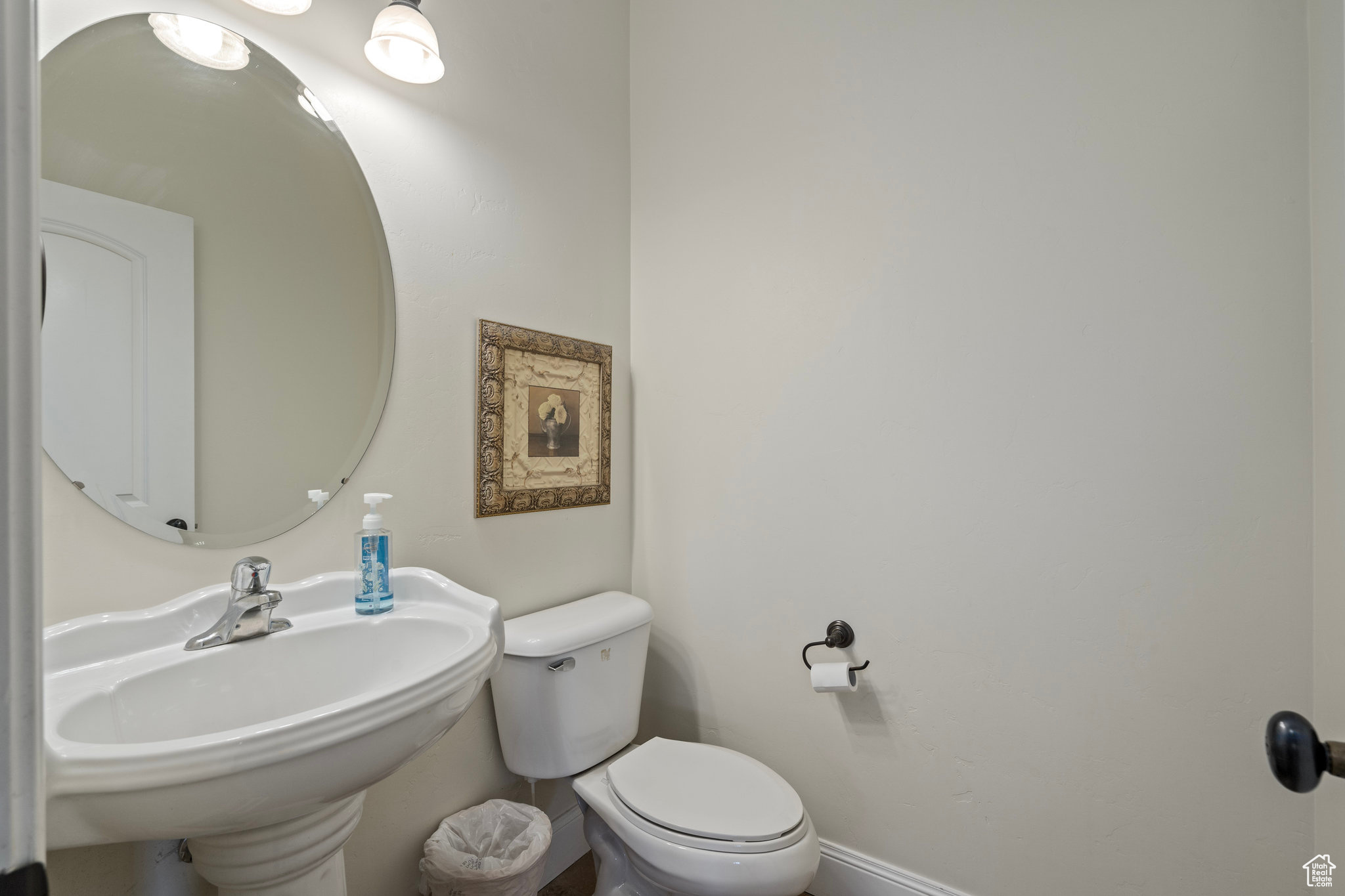 Half bath featuring toilet, baseboards, and a sink