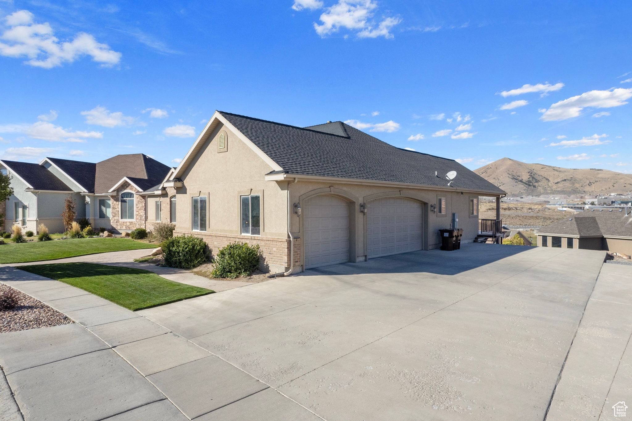 View of property exterior with concrete driveway, an attached garage, brick siding, and stucco siding