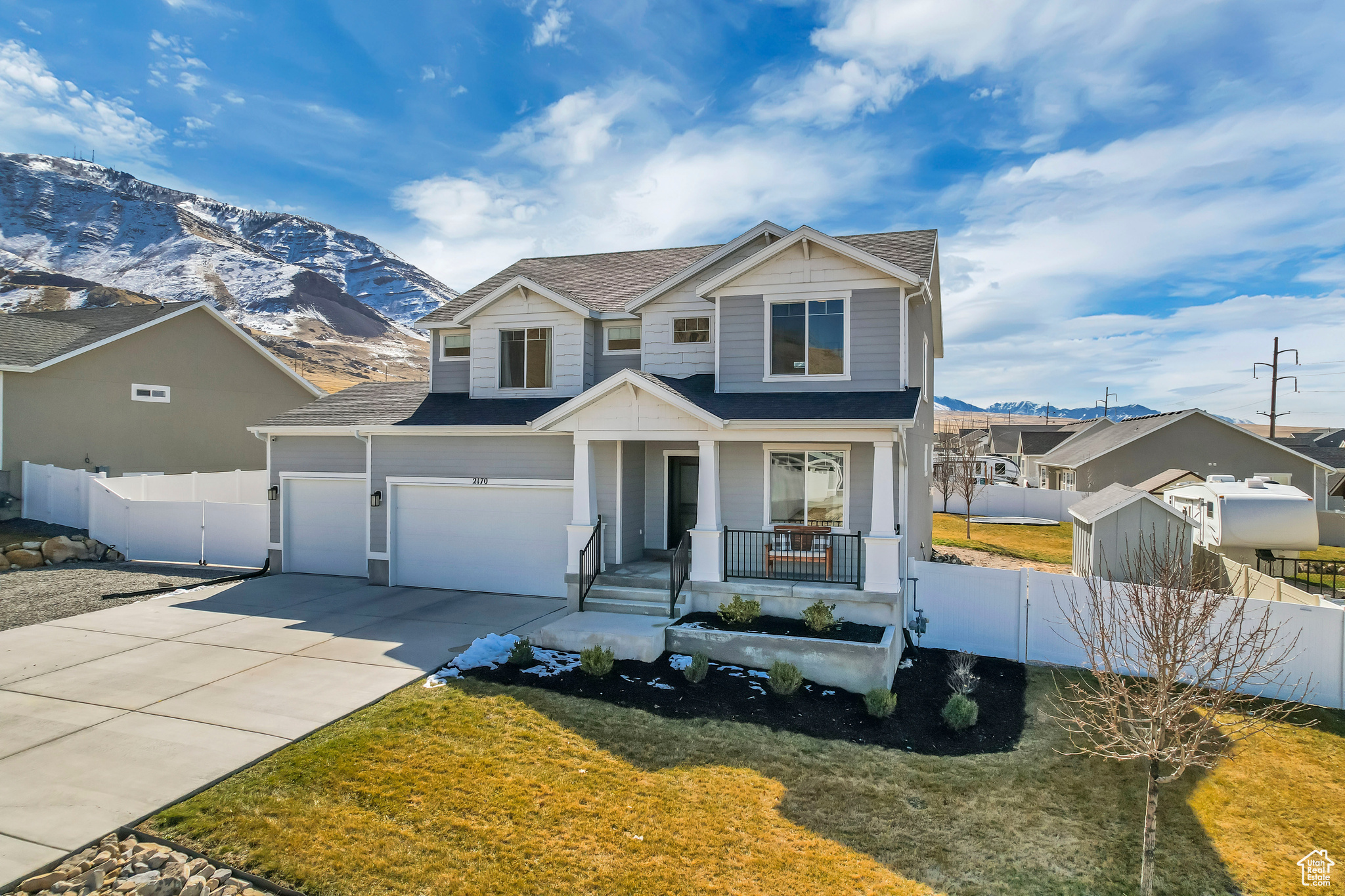 View of front of house featuring driveway, a porch, fence, a mountain view, and a garage