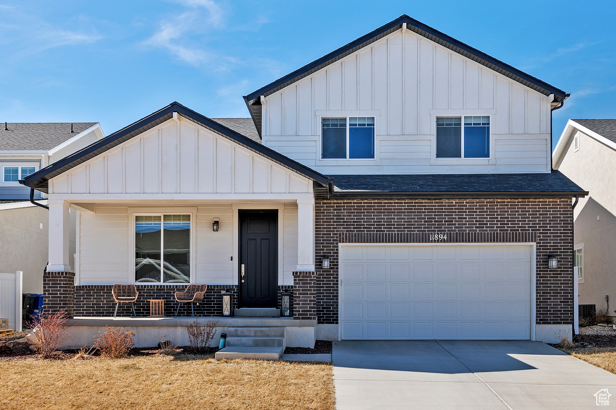 View of front of property with an attached garage, covered porch, concrete driveway, board and batten siding, and brick siding