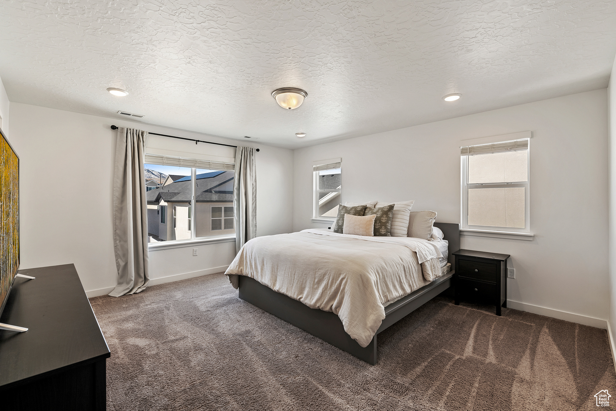 Bedroom featuring visible vents, a textured ceiling, baseboards, and carpet