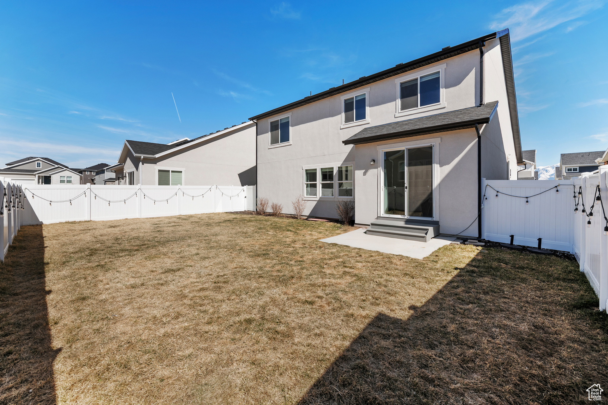 Back of property with a lawn, entry steps, a fenced backyard, and stucco siding