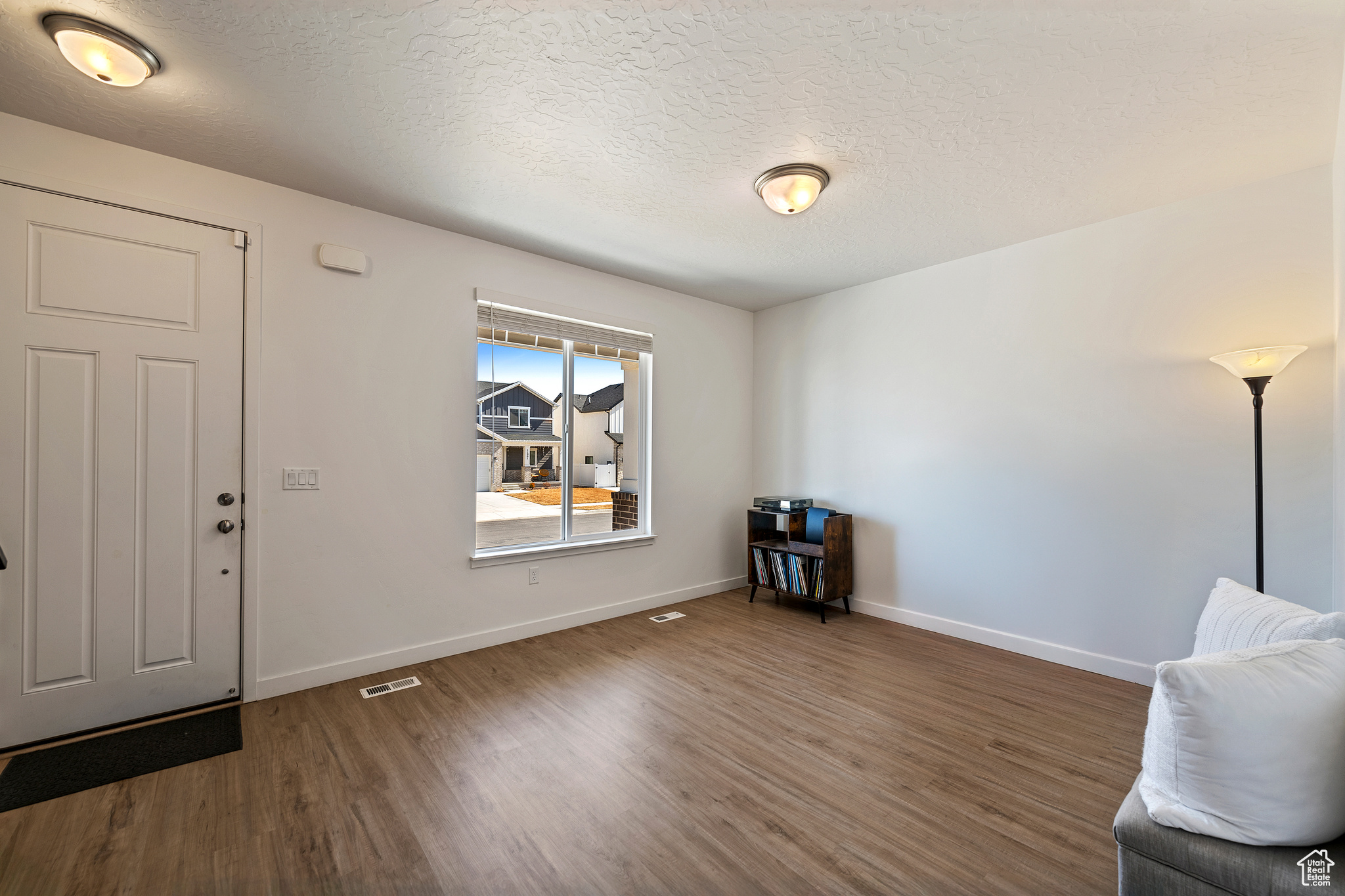 Entrance foyer with wood finished floors, baseboards, and a textured ceiling