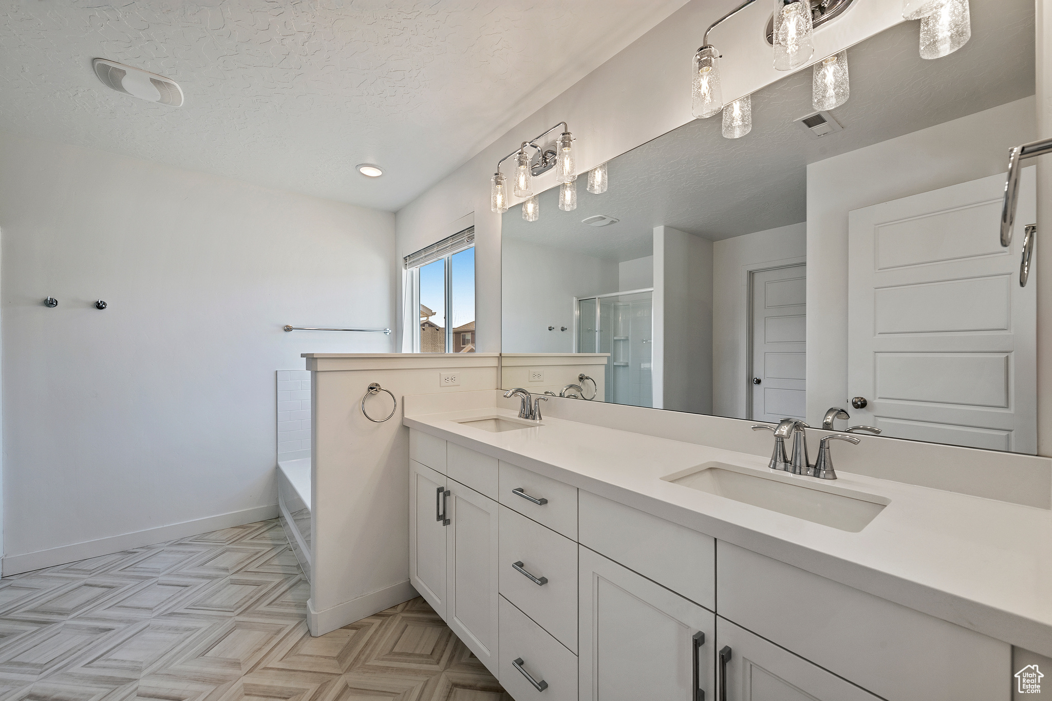 Full bath featuring a textured ceiling, visible vents, a stall shower, and a sink