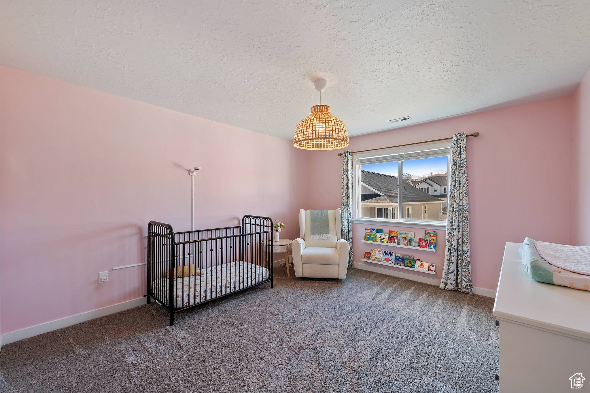 Carpeted bedroom featuring visible vents, a textured ceiling, baseboards, and a nursery area