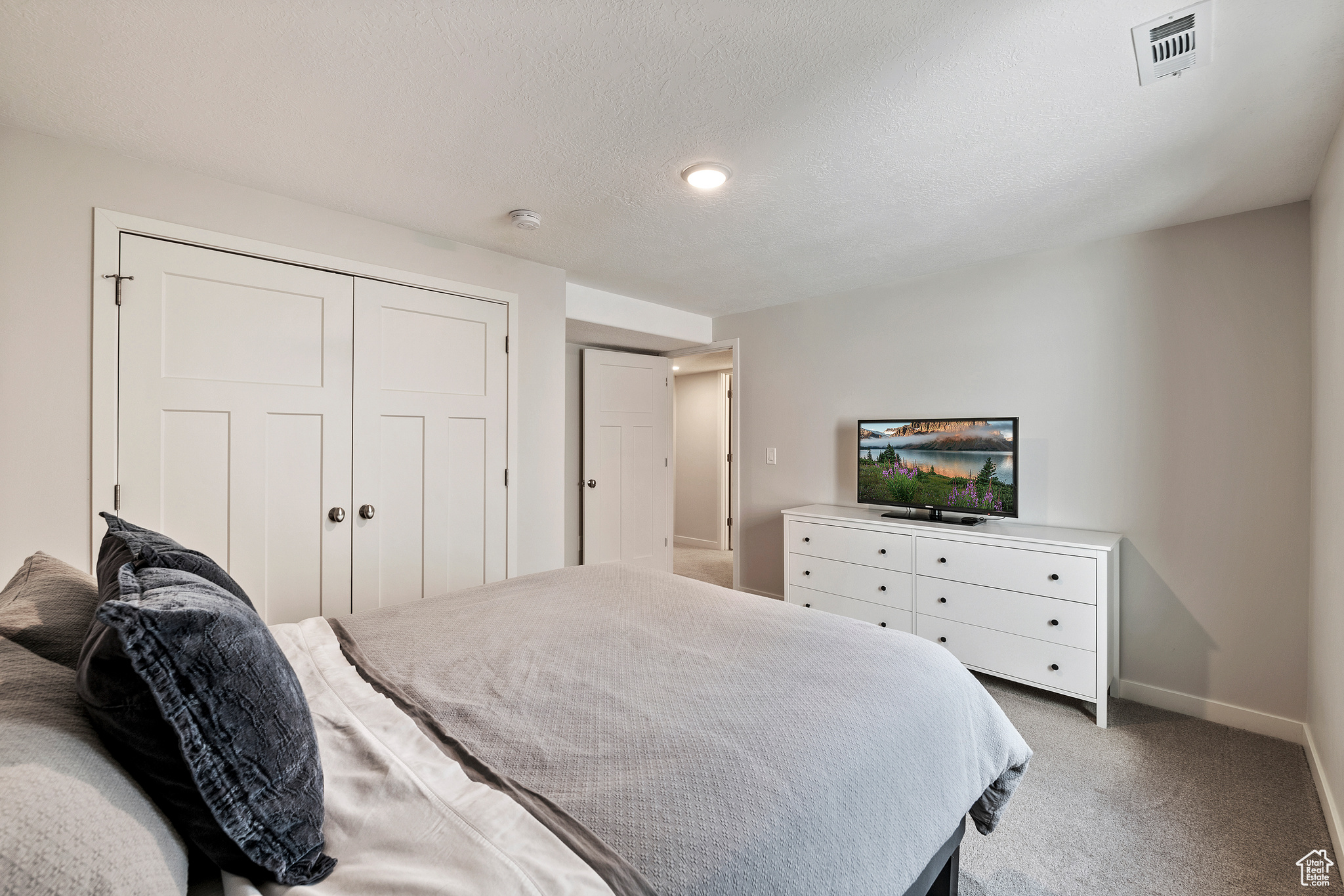 Bedroom with visible vents, baseboards, carpet, a closet, and a textured ceiling
