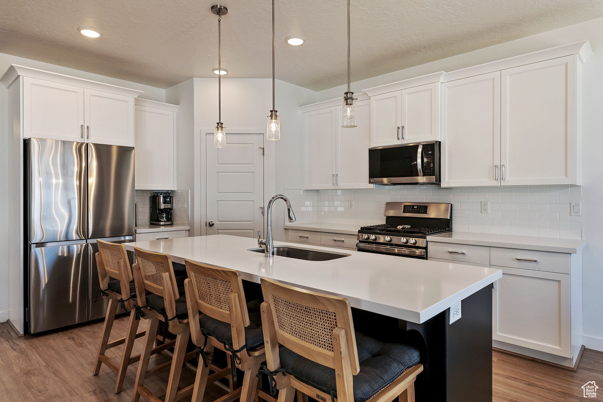 Kitchen with a sink, a kitchen bar, appliances with stainless steel finishes, and wood finished floors