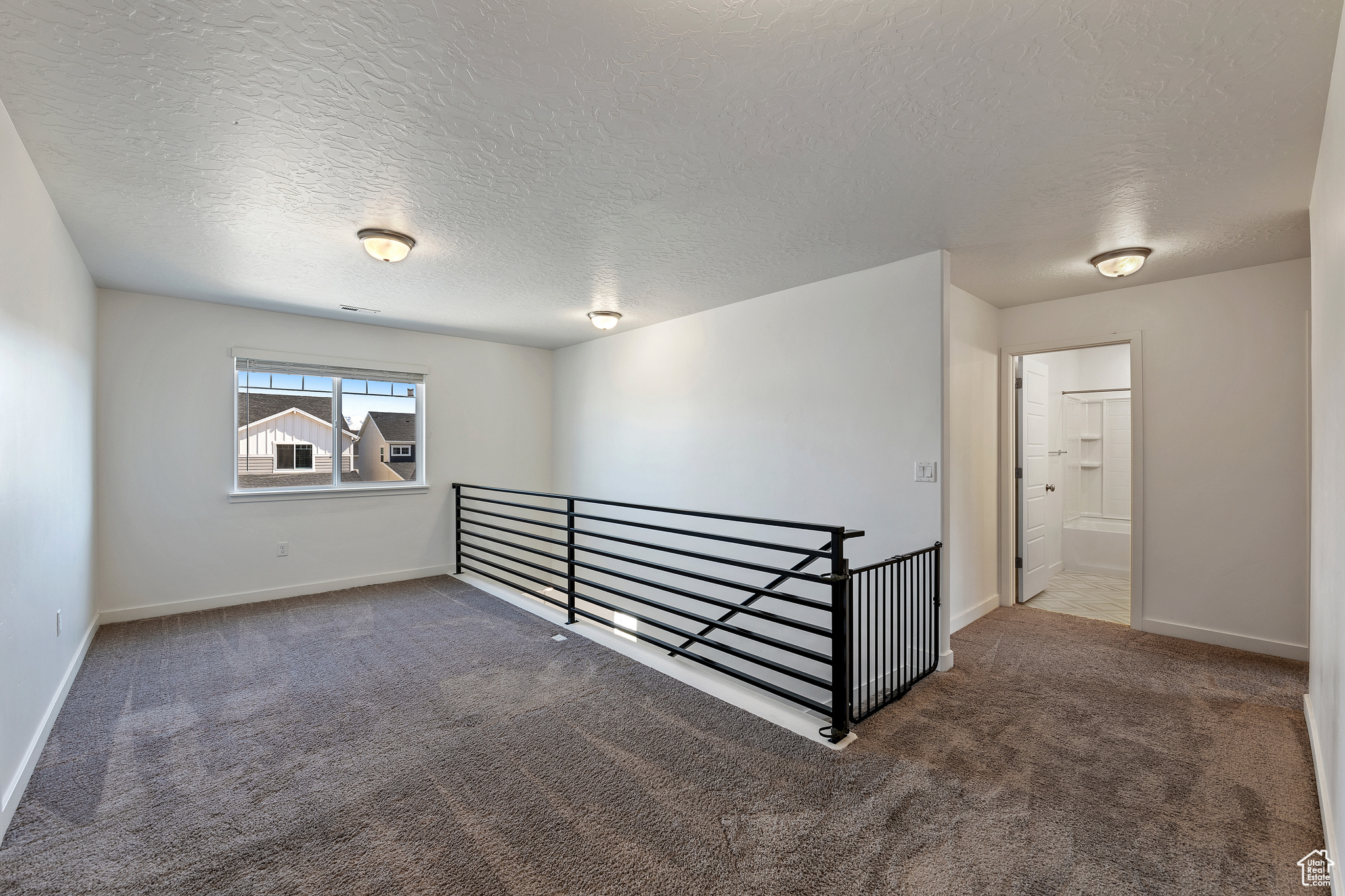 Carpeted empty room with baseboards and a textured ceiling