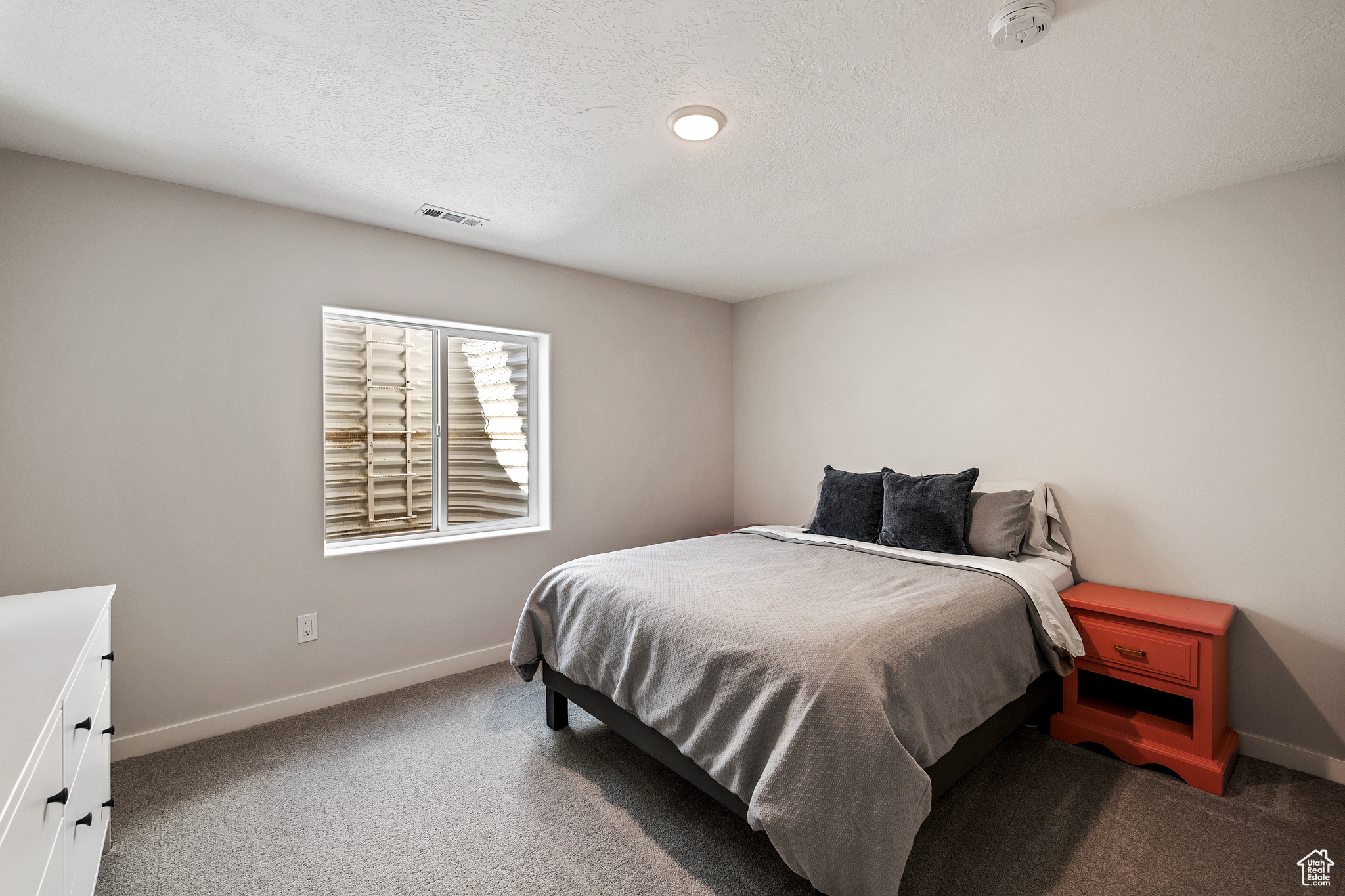 Carpeted bedroom with baseboards, visible vents, and a textured ceiling