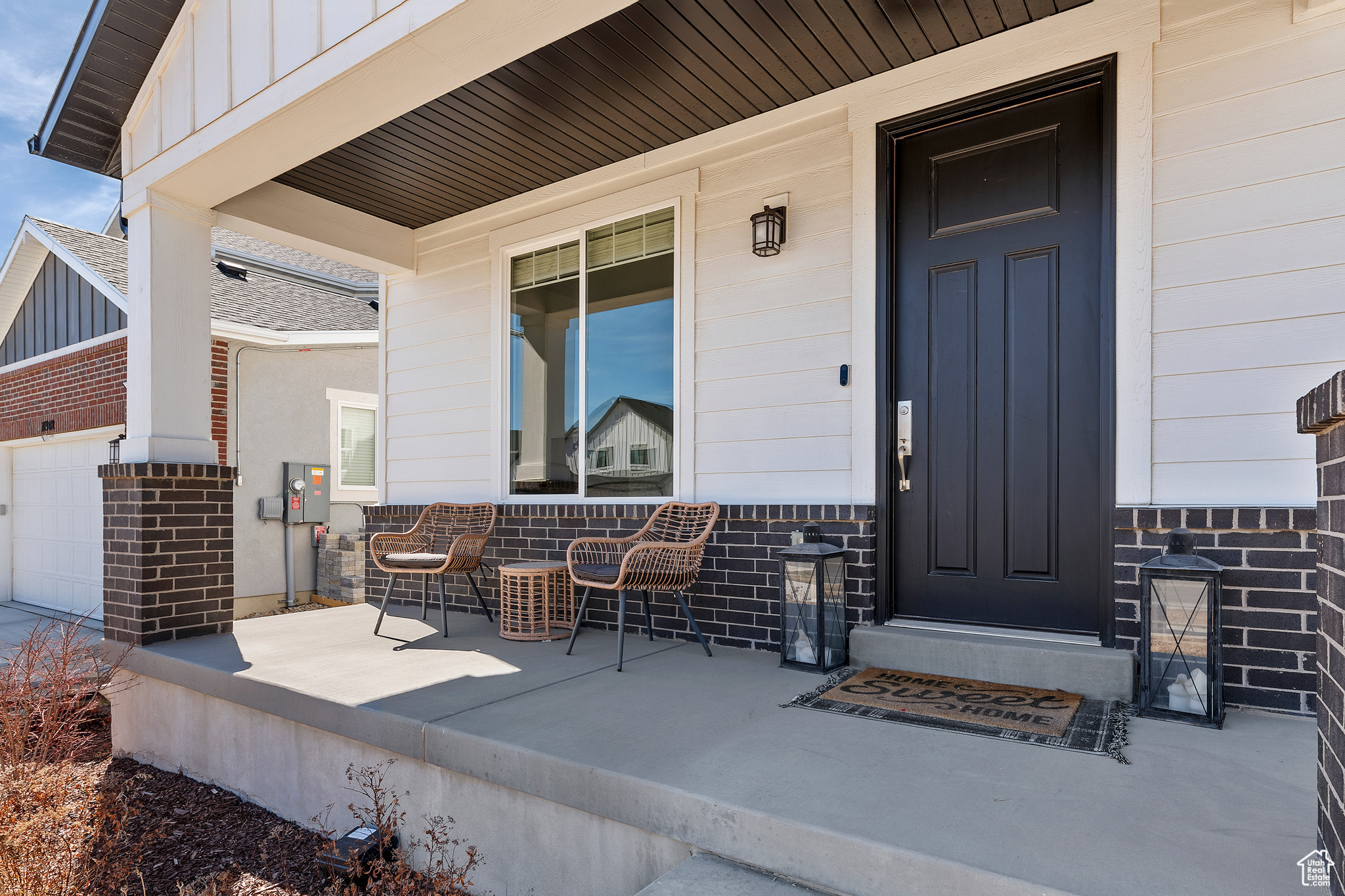 Property entrance featuring brick siding, a garage, a porch, and board and batten siding
