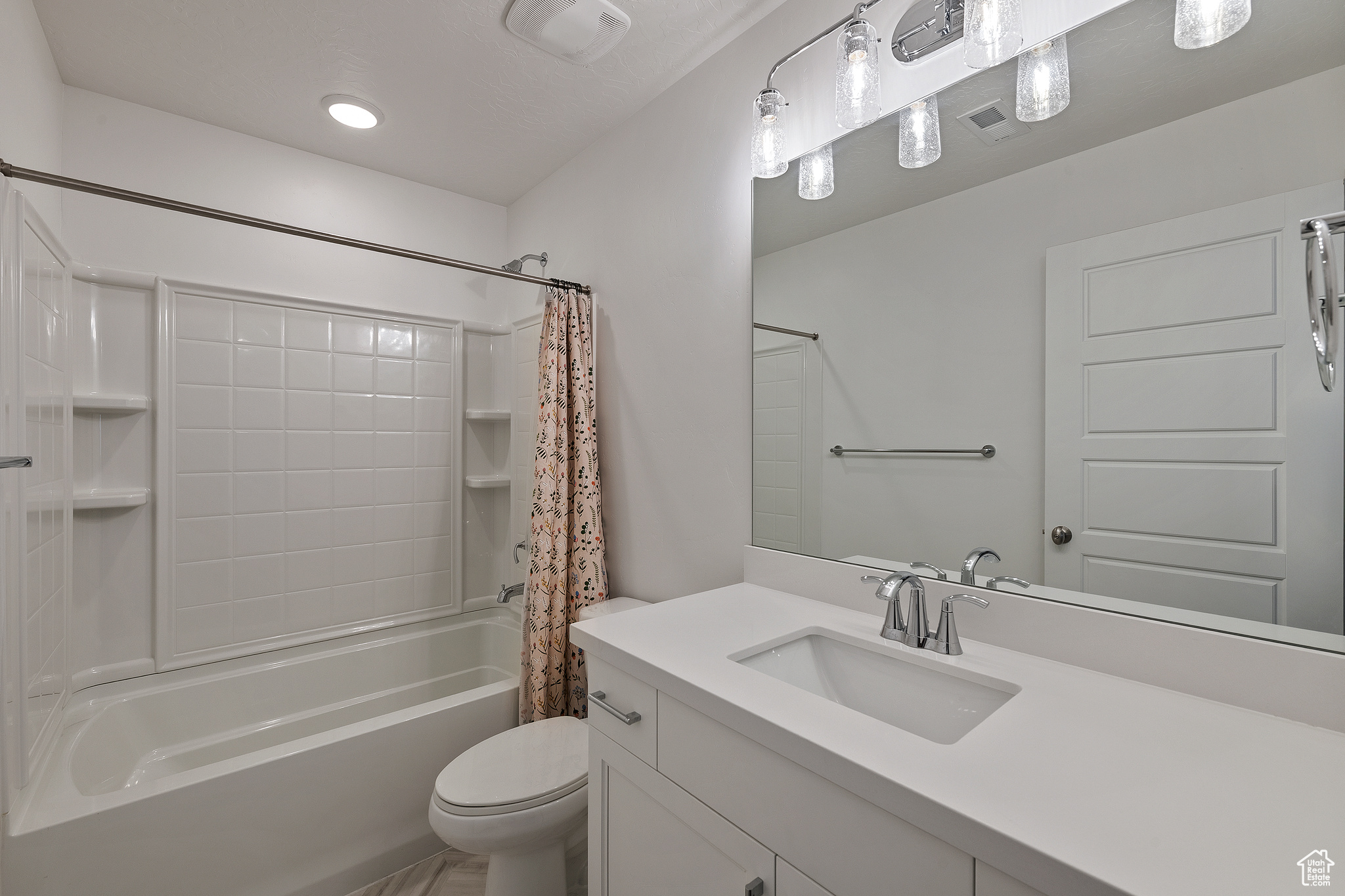 Bathroom with visible vents, toilet, shower / bath combo with shower curtain, and vanity