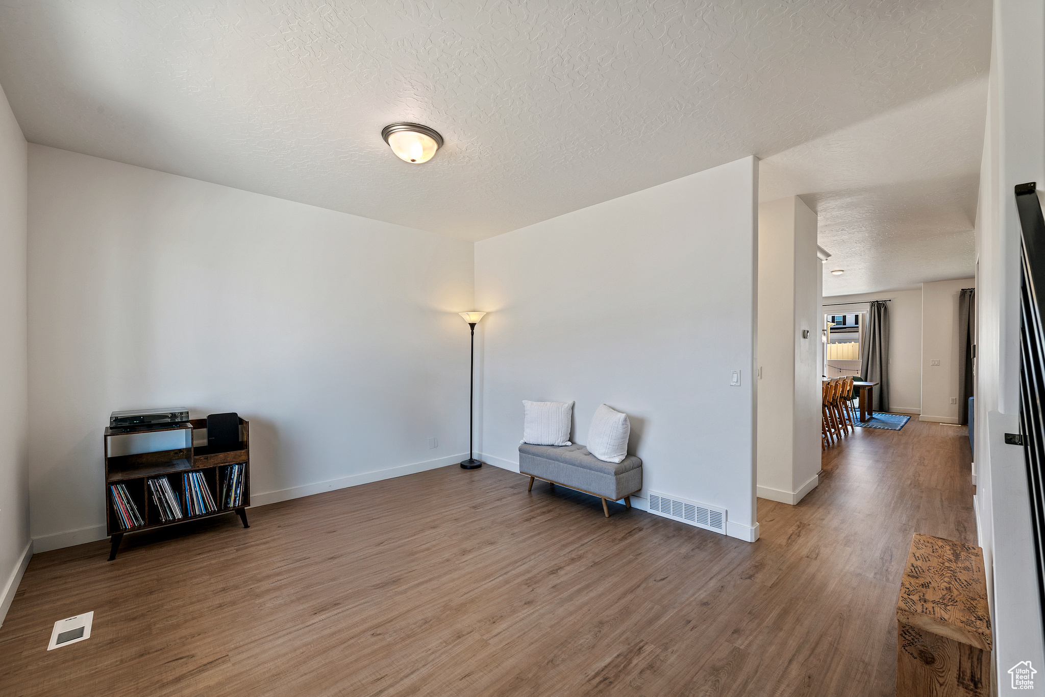 Living area featuring visible vents, a textured ceiling, baseboards, and wood finished floors