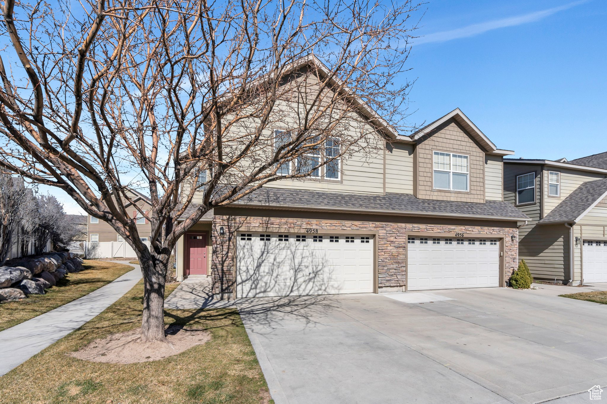 View of front of home featuring stone siding, a garage, driveway, and roof with shingles