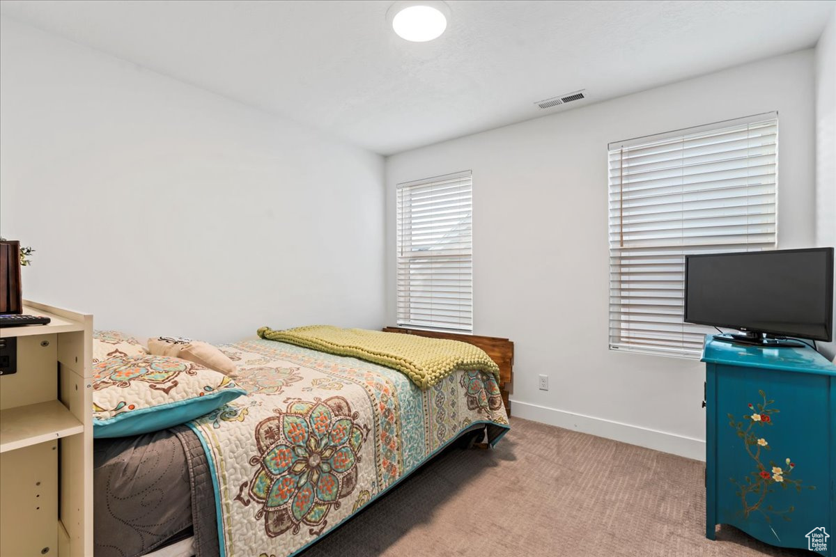 Carpeted bedroom featuring visible vents and baseboards