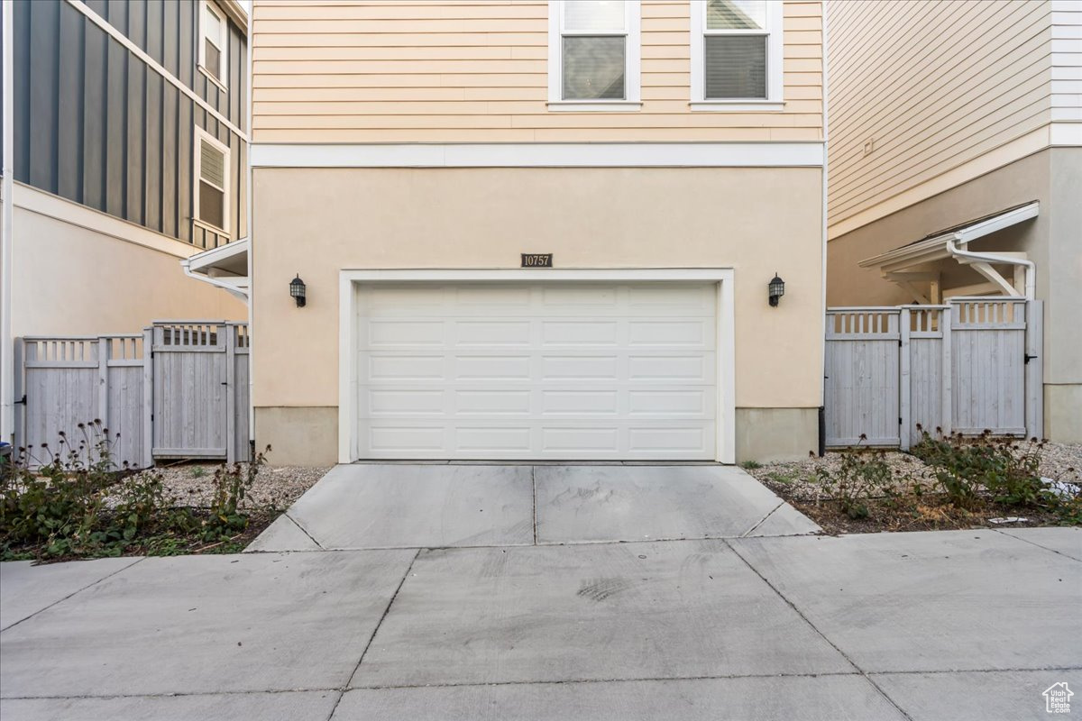 Garage featuring fence and concrete driveway