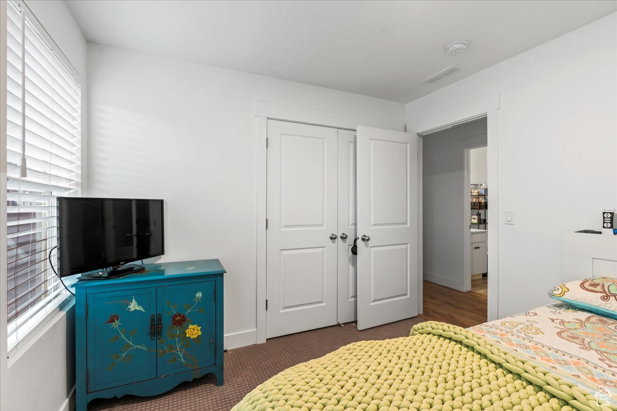 Carpeted bedroom with visible vents and a closet