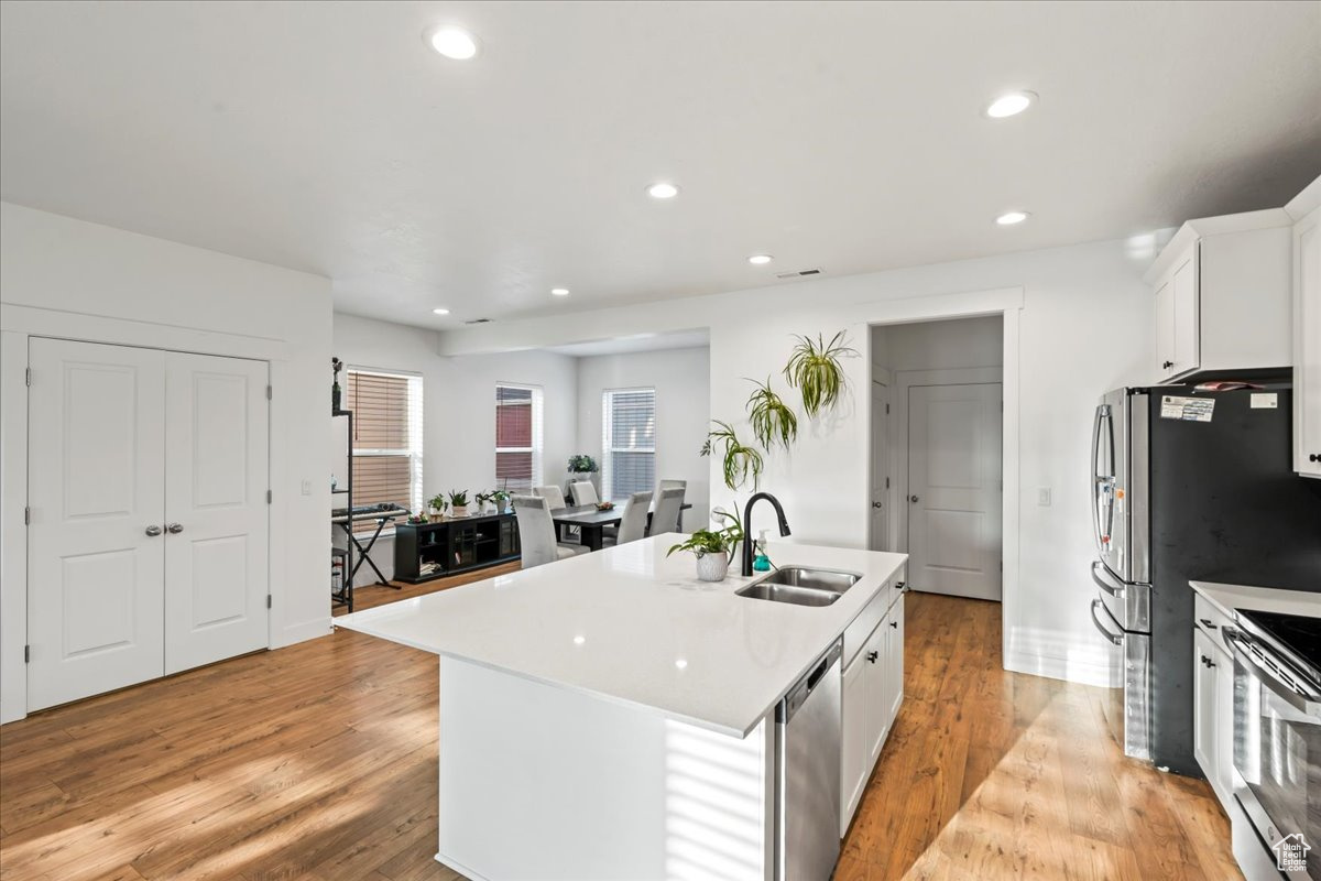 Kitchen featuring recessed lighting, stainless steel appliances, a sink, light countertops, and light wood finished floors