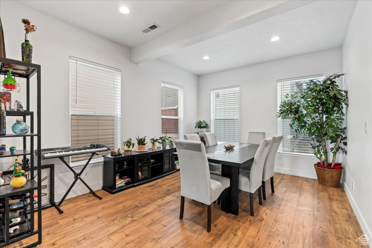 Dining room featuring light wood finished floors, visible vents, beamed ceiling, and recessed lighting