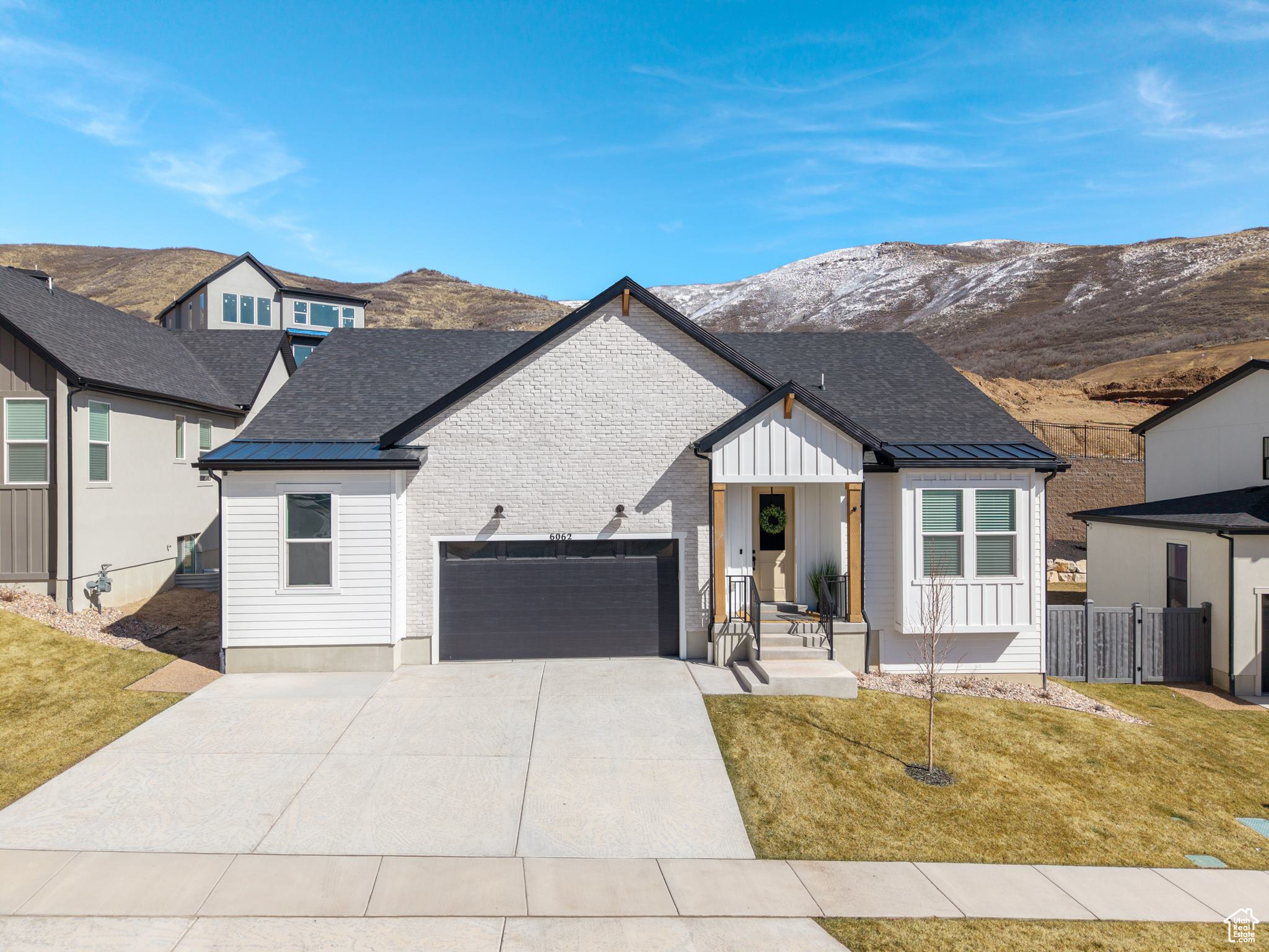 Modern inspired farmhouse with a front yard, a mountain view, fence, and a garage