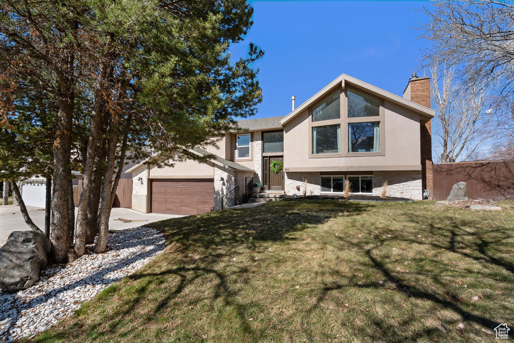 View of front of property with stucco siding, a chimney, a front lawn, and fence