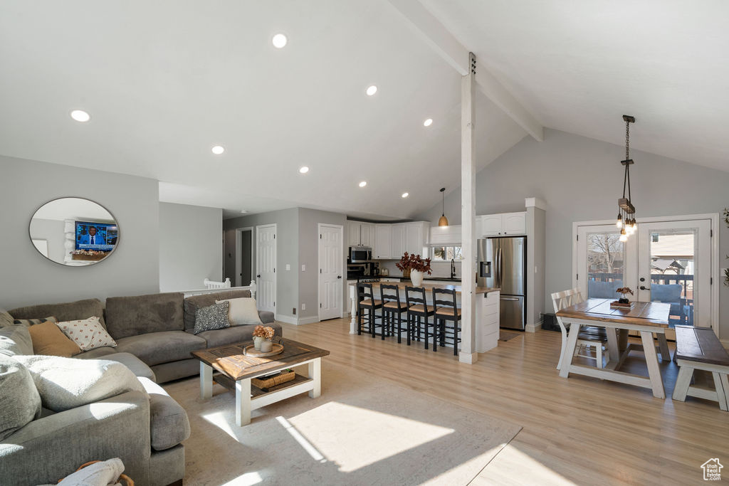 Living area with light wood finished floors, baseboards, beamed ceiling, recessed lighting, and high vaulted ceiling