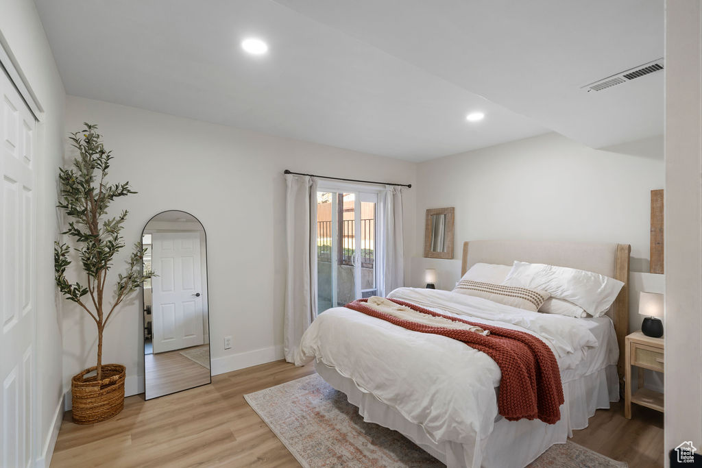 Bedroom with wood finished floors, visible vents, baseboards, recessed lighting, and access to exterior