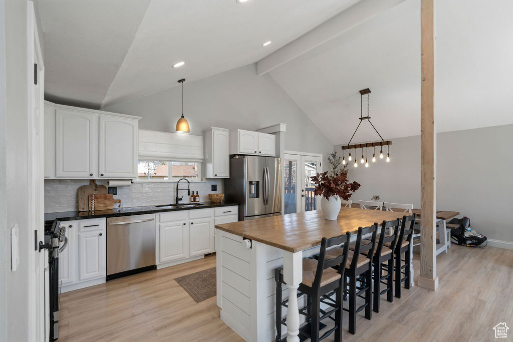 Kitchen with a sink, white cabinets, light wood finished floors, and stainless steel appliances