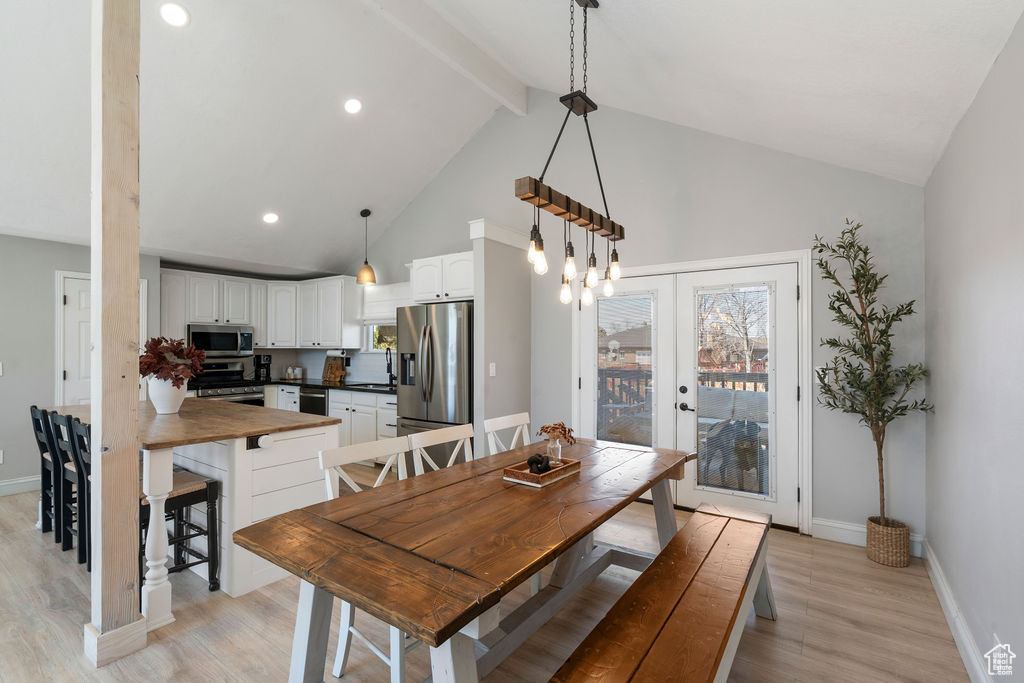 Dining room featuring beamed ceiling, plenty of natural light, high vaulted ceiling, and light wood finished floors