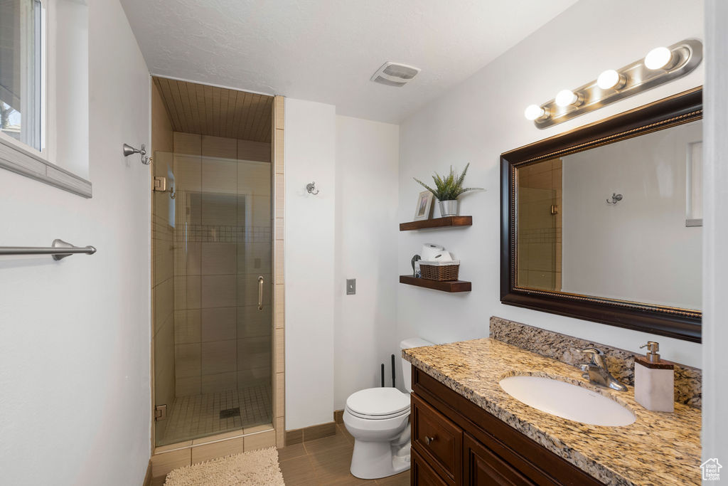 Bathroom with visible vents, toilet, a shower stall, baseboards, and vanity