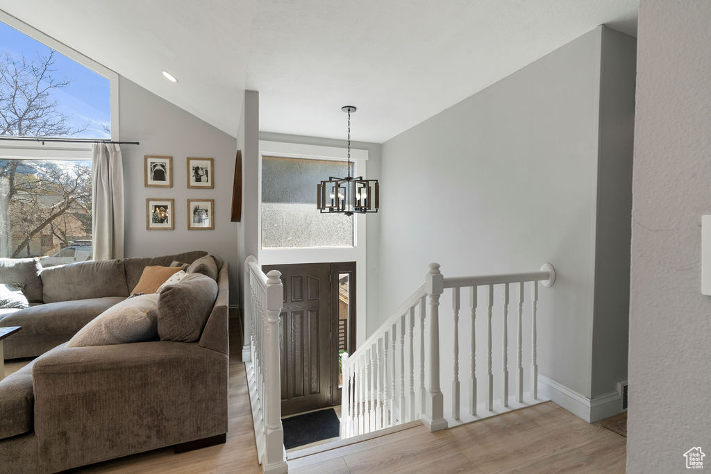 Entrance foyer featuring a notable chandelier, high vaulted ceiling, baseboards, and wood finished floors