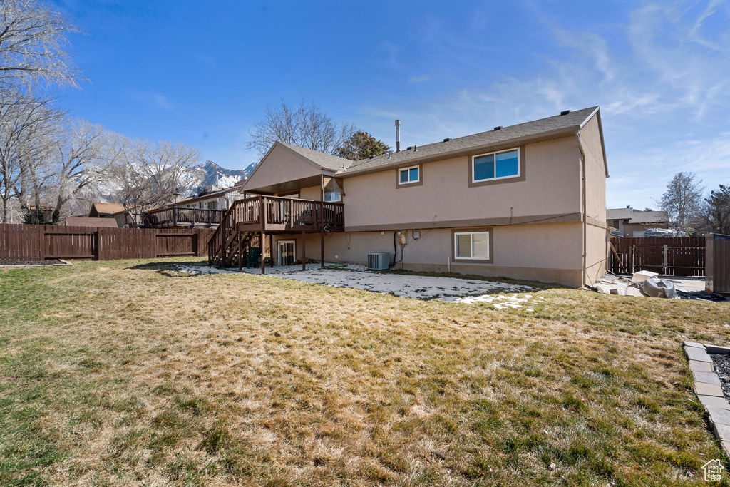 Rear view of property with stairway, central AC, a yard, a fenced backyard, and a deck